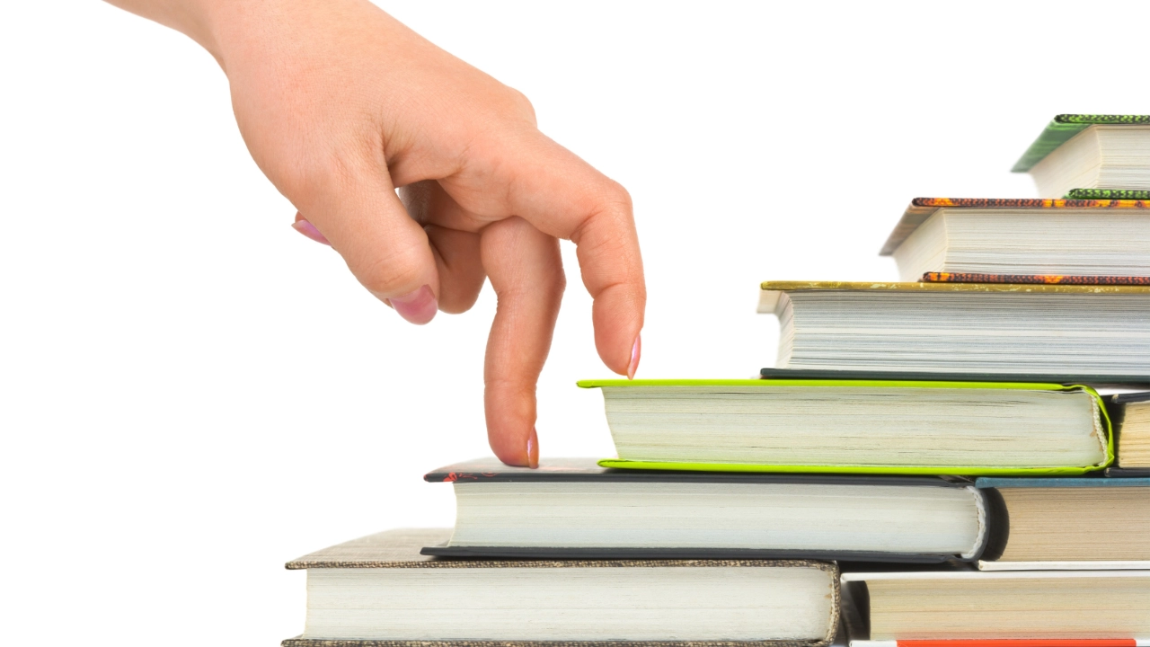 Hand läuft symbolisch eine Büchertreppe hinauf