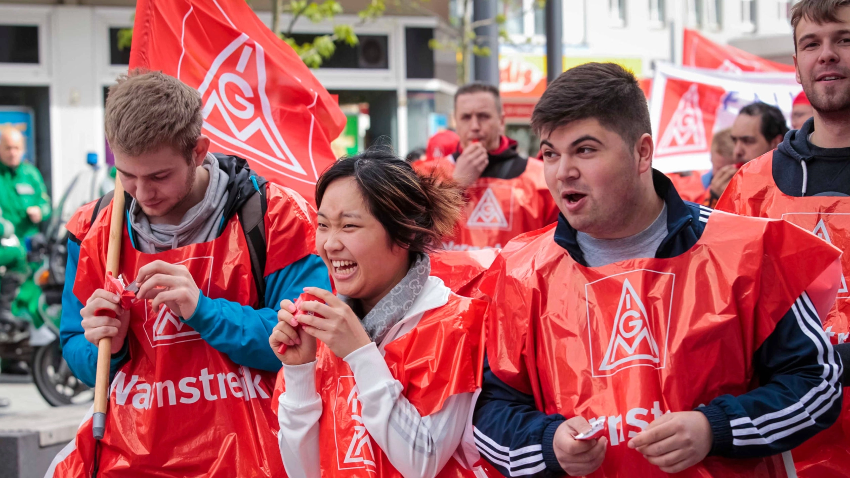Eine junge lachende Frau und zwei Männer bei einer Aktion.