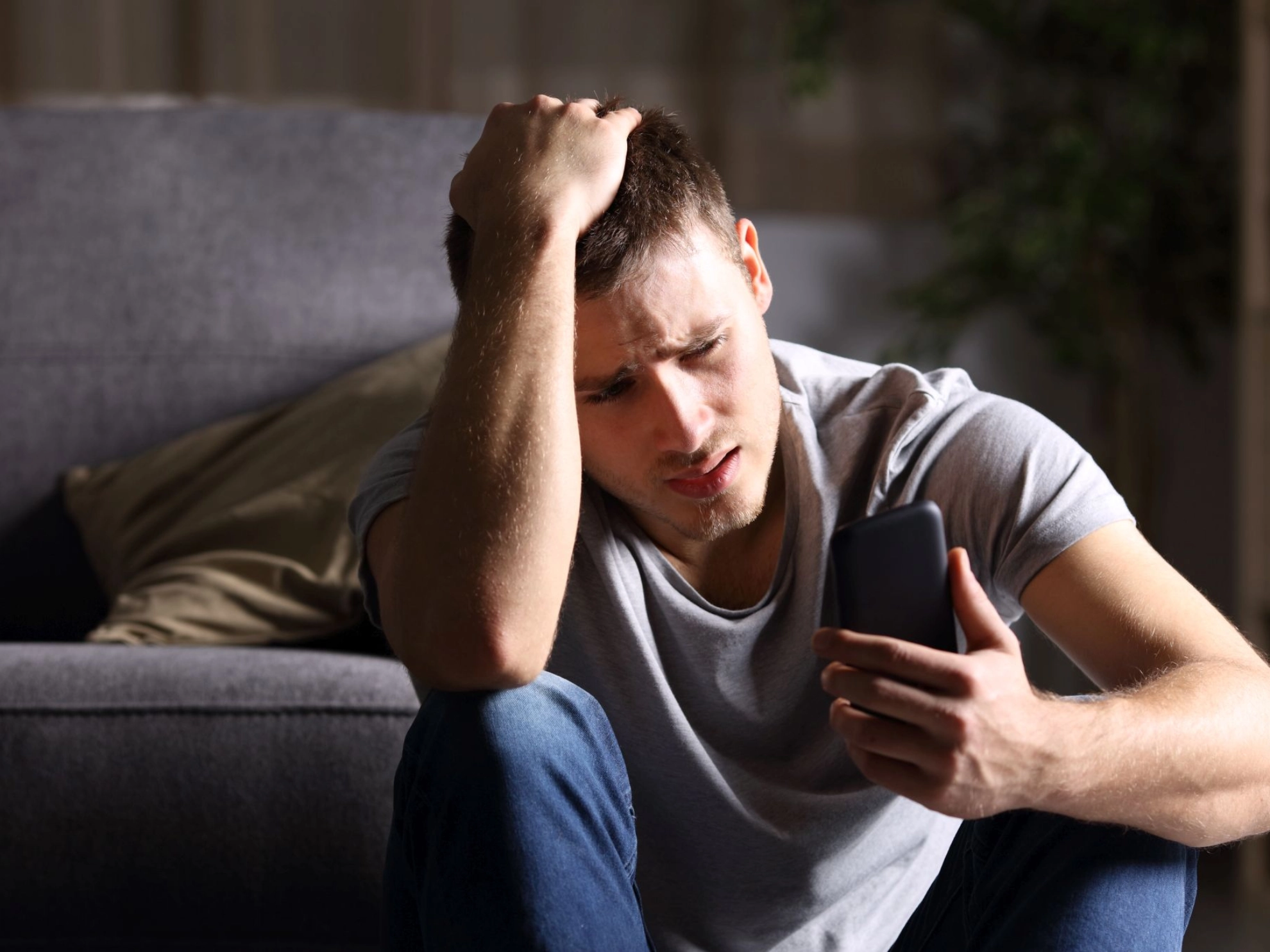 junger Mann blickt gestresst auf sein Smartphone