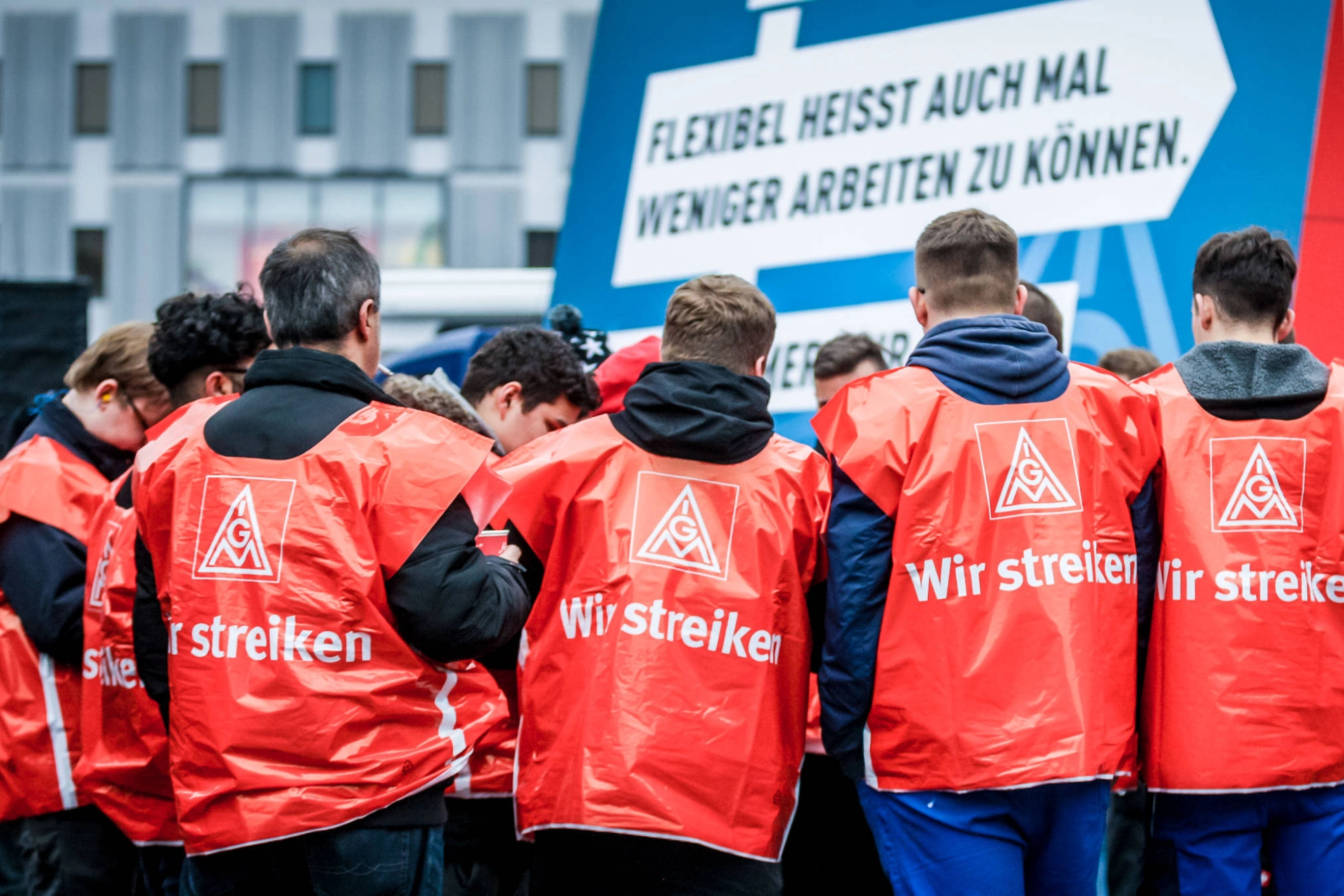 Eine Gruppe junge Männer mit roten Streikwesten.