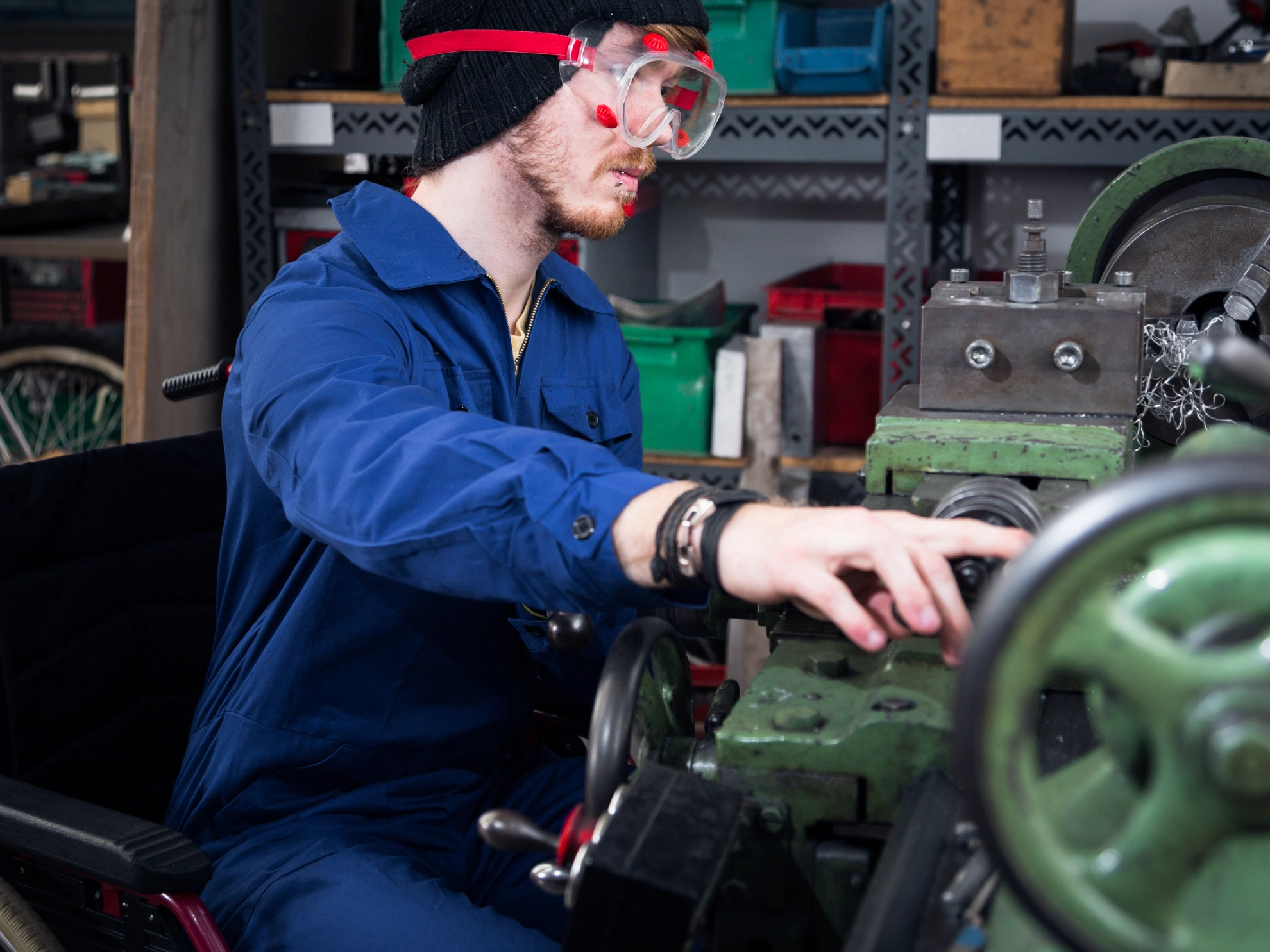 Junger Mechaniker an der Drehmaschine im Rollstuhl