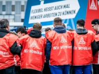 Eine Gruppe junge Männer mit roten Streikwesten.